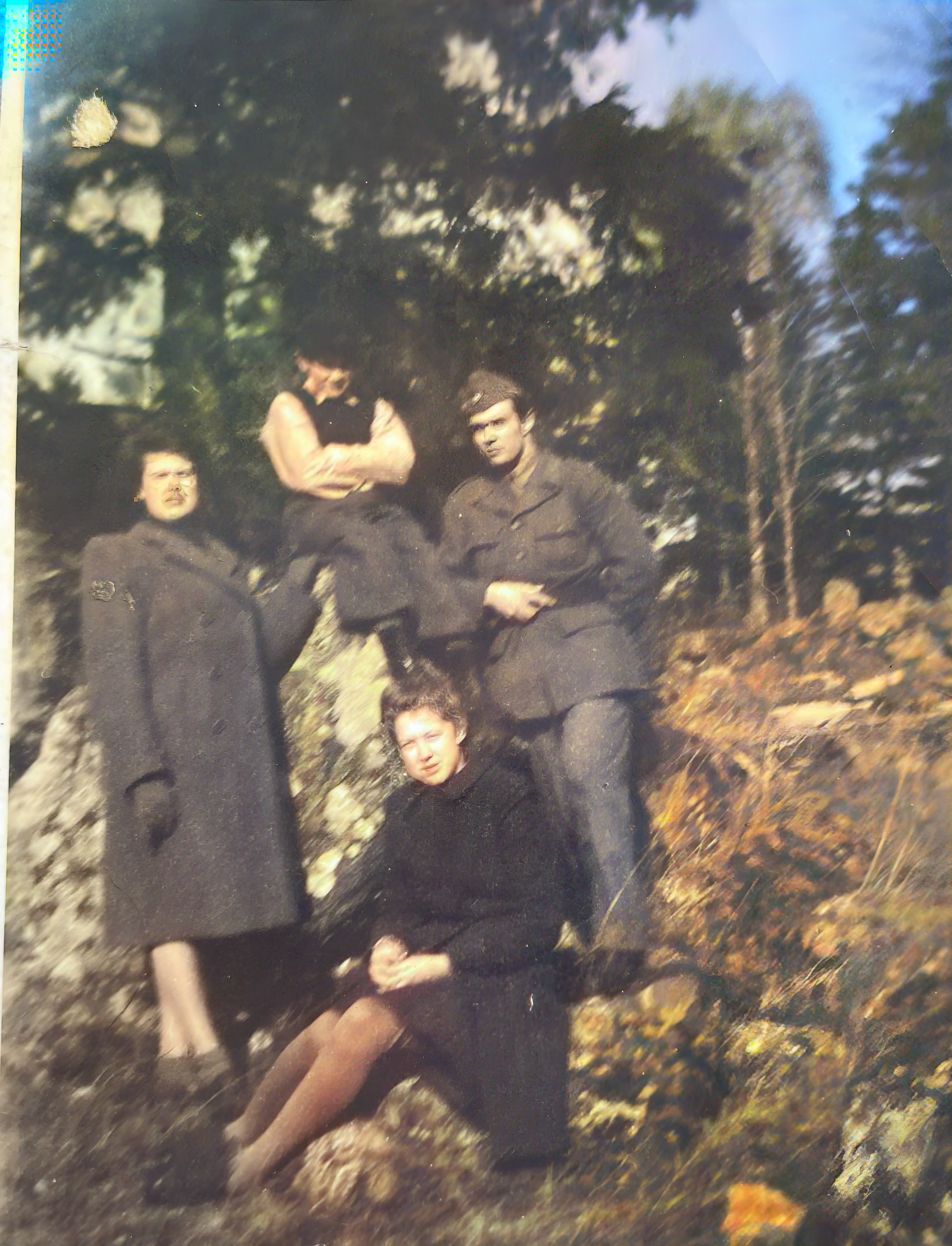 Tre personer utomhus bland stenar och buskar